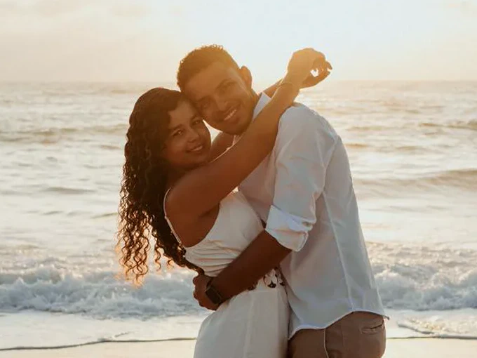 Ismael e Janaina abraçados na praia ao pôr do sol